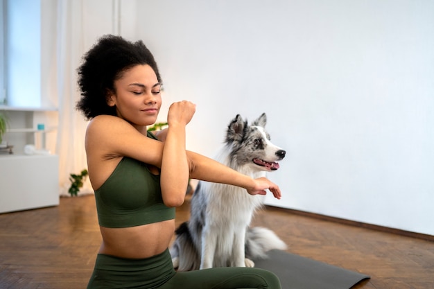 Person, die in Begleitung ihres Haustieres Yoga macht
