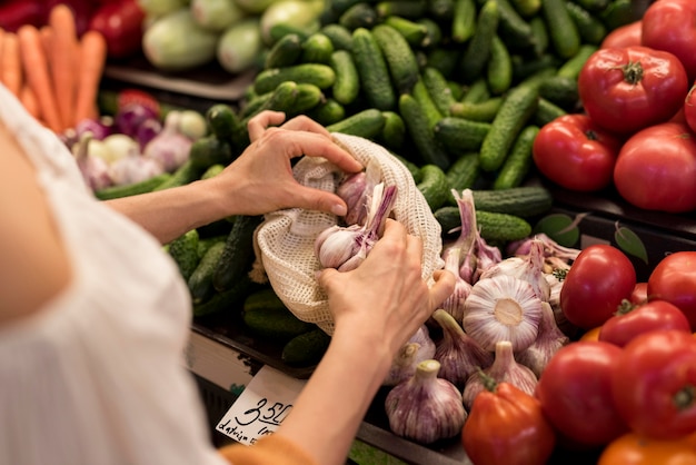 Kostenloses Foto person, die knoblauch vom marktplatz hohe ansicht kauft