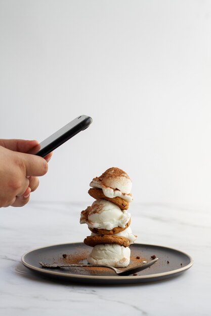 Person, die mit dem smartphone ein dessert mit kakaopulver fotografiert
