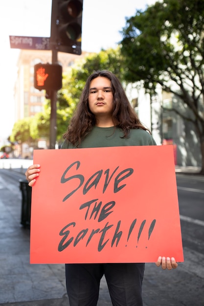 Kostenloses Foto person, die mit plakat für den weltumwelttag im freien protestiert