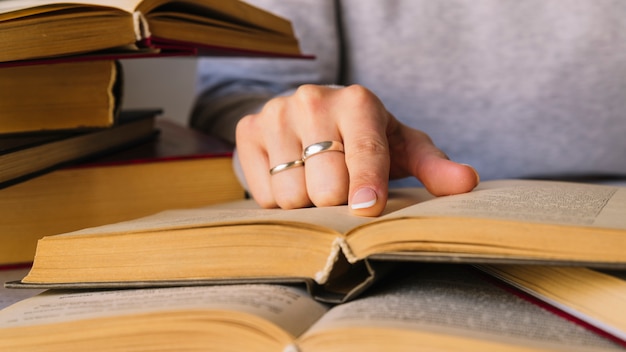 Kostenloses Foto person, die neben buchstapel studiert