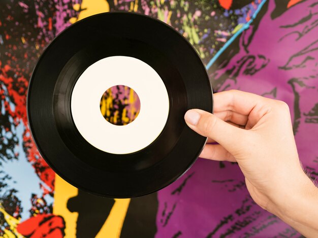 Person, die Retro- Vinylscheibe nahe mehrfarbigem wallperson hol hält