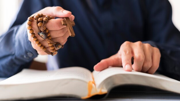 Person, die Rosenkranz mit Kreuz hält und betet