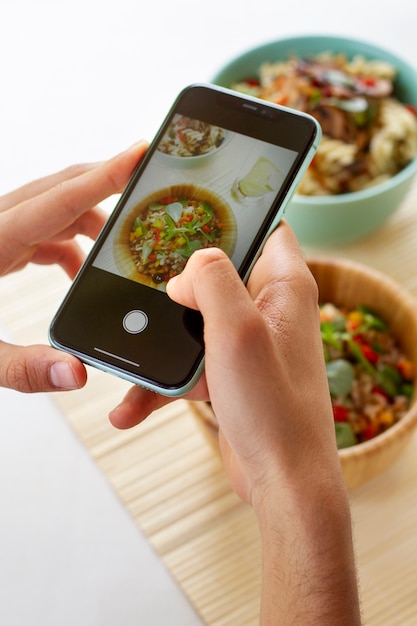 Person, die Schüsseln mit Essen mit Smartphone fotografiert