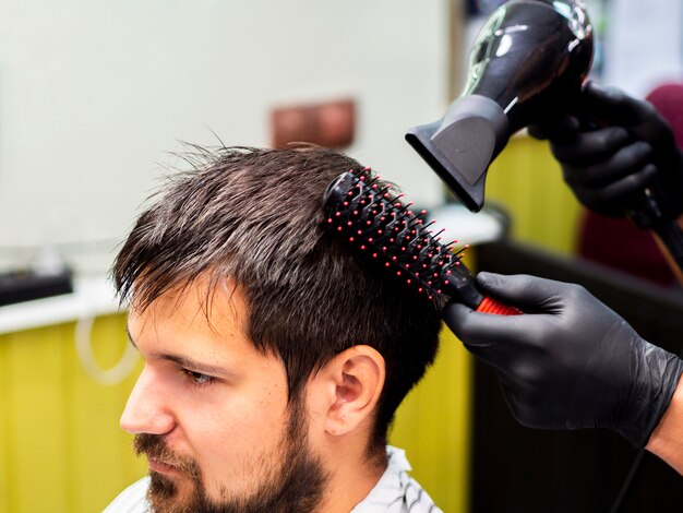 Person, die sein Haar mit Trockner trocknen lässt