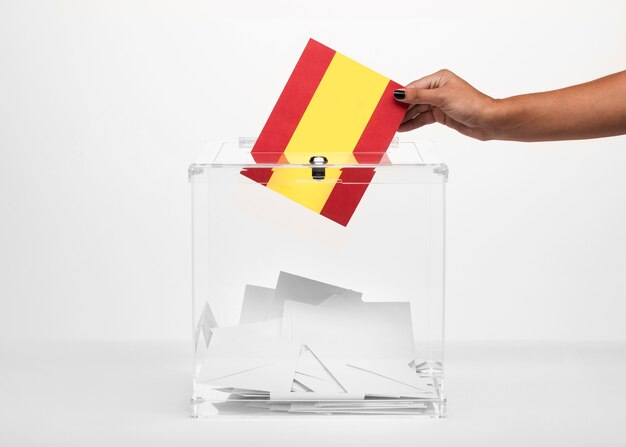 Person, die Spanien-Flaggenkarte in Wahlurne setzt