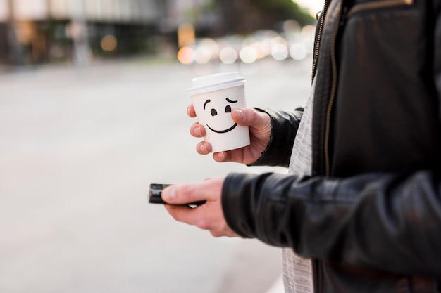 Person, die Tasse und Smartphone hält