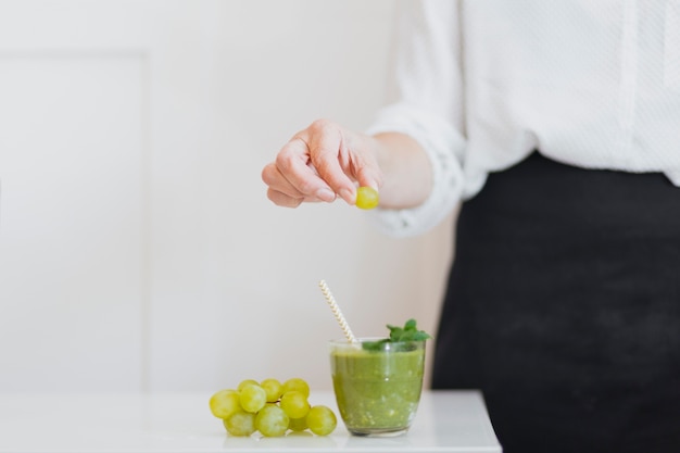 Kostenloses Foto person, die traube zu smoothie setzt