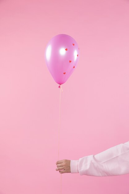 Person, die violetten Ballon mit Verzierungsherzen und -faden hält