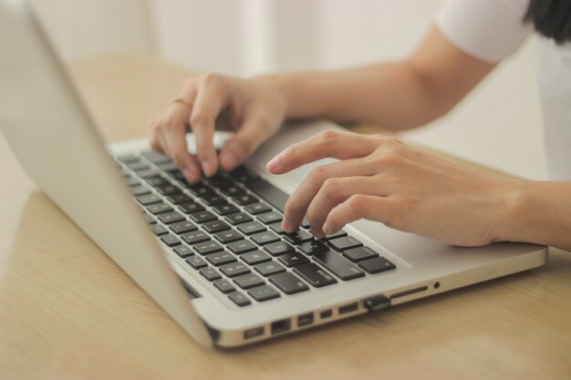 Person, die vor einem Schreibtisch sitzt und auf der Tastatur des Laptops tippt