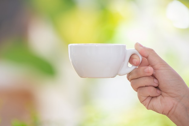 Person hält eine weiße Kaffeetasse