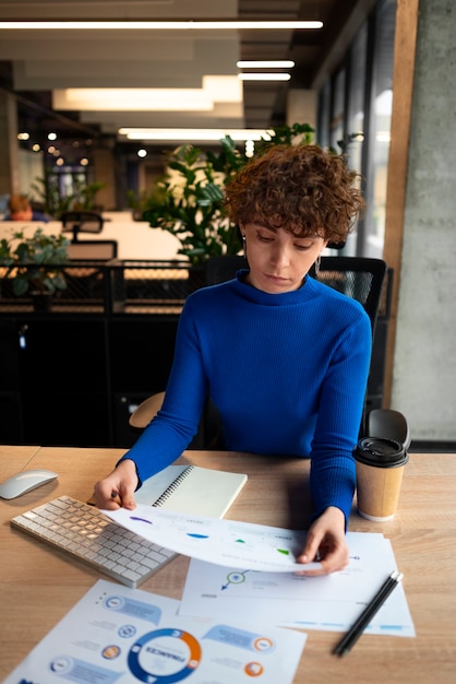 Kostenloses Foto person im büro, die finanzdiagramme analysiert und überprüft