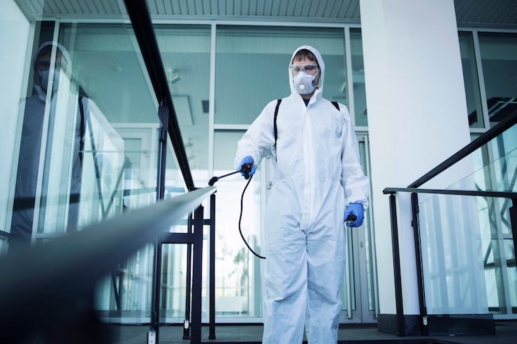 Kostenlose Foto person im weißen chemikalienschutzanzug, die öffentliche bereiche desinfiziert, um die ausbreitung des hoch ansteckenden koronavirus zu stoppen