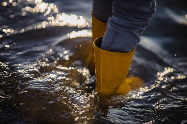 Person in blauen Jeans und gelben Stiefeln, die auf Wasser stehen