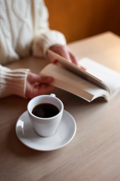 Person in einem Café, die ein Buch liest, während sie Kaffee trinkt