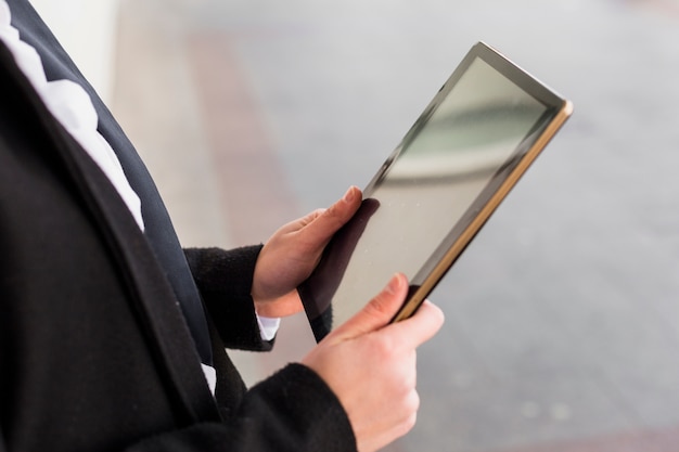 Person in schwarz mit Tablet außerhalb