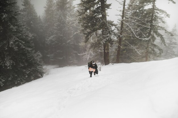 Person mit dem Brennholz gehend auf Schnee