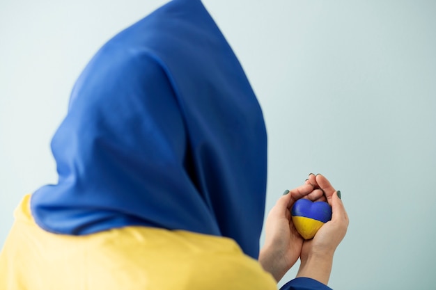 Person mit ukrainischer Flagge, die einen in Blau und Gelb gemalten Stein hält