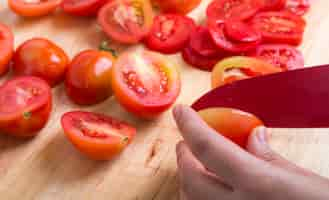 Kostenloses Foto person schneiden tomaten in scheiben geschnitten