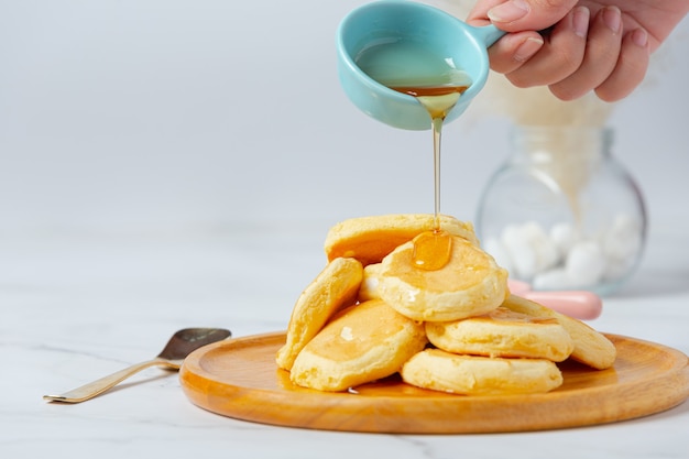 Pfannkuchen mit Ahornsirup in Platte auf weißem Hintergrund