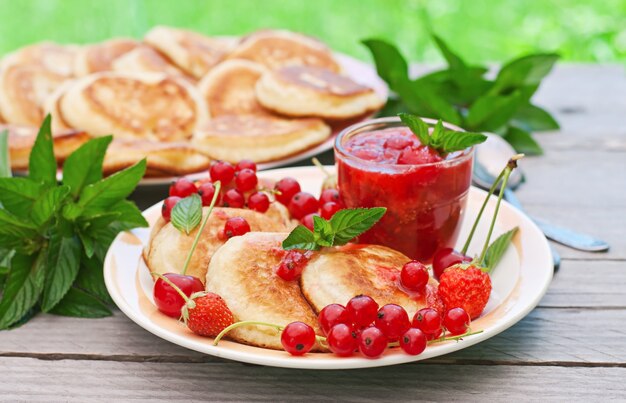 Pfannkuchen mit Beeren auf einem Holztisch in einem Sommergarten