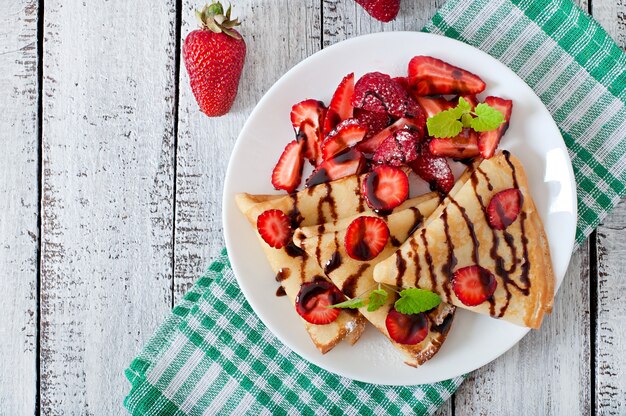 Pfannkuchen mit Erdbeeren und Schokolade mit Minzblatt verziert