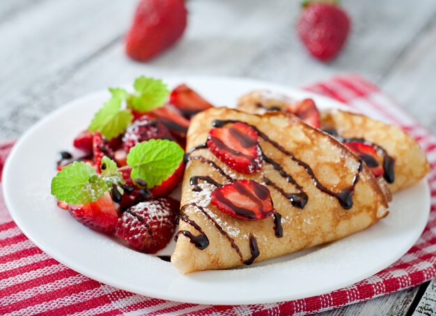 Pfannkuchen mit Erdbeeren und Schokolade mit Minzblatt verziert