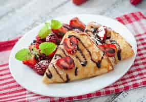 Kostenloses Foto pfannkuchen mit erdbeeren und schokolade mit minzblatt verziert