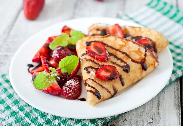 Pfannkuchen mit Erdbeeren und Schokolade mit Minzblatt verziert