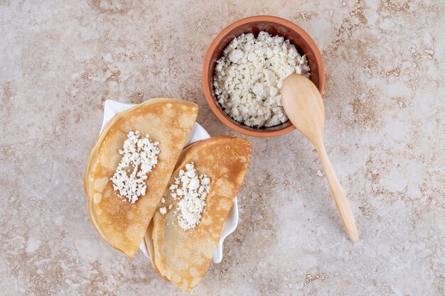 Pfannkuchen mit Quark und einem Holzlöffel rollen