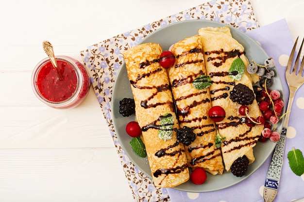 Pfannkuchen mit Schokolade, Marmelade und Beeren. Leckeres Frühstück. Flach liegen. Draufsicht