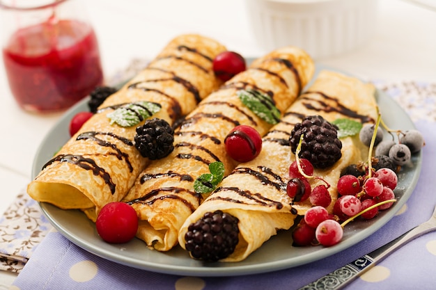 Pfannkuchen mit Schokolade, Marmelade und Beeren. Leckeres Frühstück.