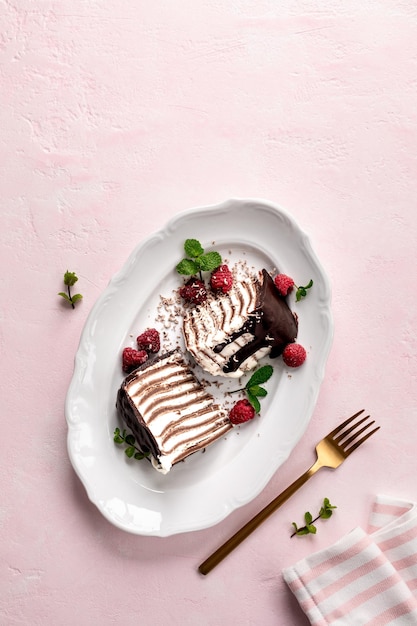 Pfannkuchen-Schokoladenkuchen mit frischen Himbeeren auf einem rosa Hintergrund