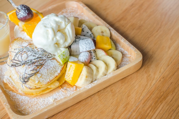 Pfannkuchen und Obst mit Eis auf dem Tisch.