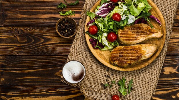 Pfeffer und Bier in der Nähe von Salat und Hühnchen