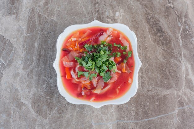 Pfefferige Borschsuppe mit Koriandergarnitur auf Marmor.