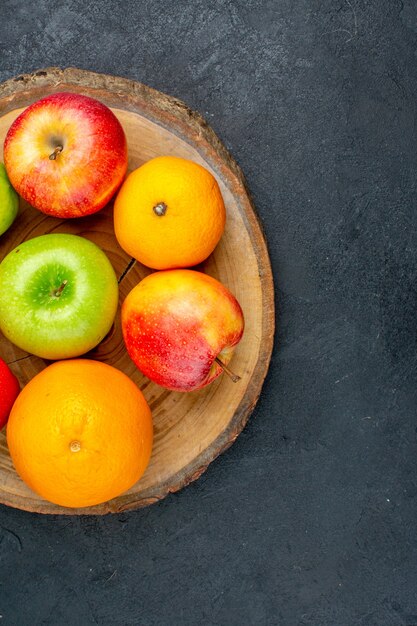 Äpfel der oberen Hälfte sehen Zitronenorangen auf Holzbrett auf dunkler Oberfläche an