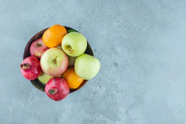 Äpfel, Granatapfel und Mandarinen in einer silbernen Schüssel.