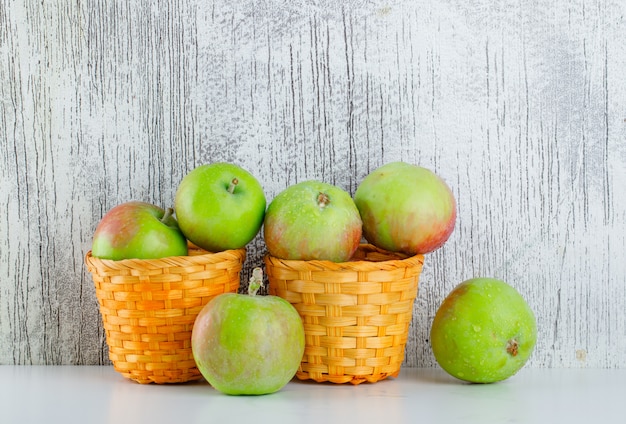 Äpfel in Weidenkörben auf weiß und grungy. Seitenansicht.