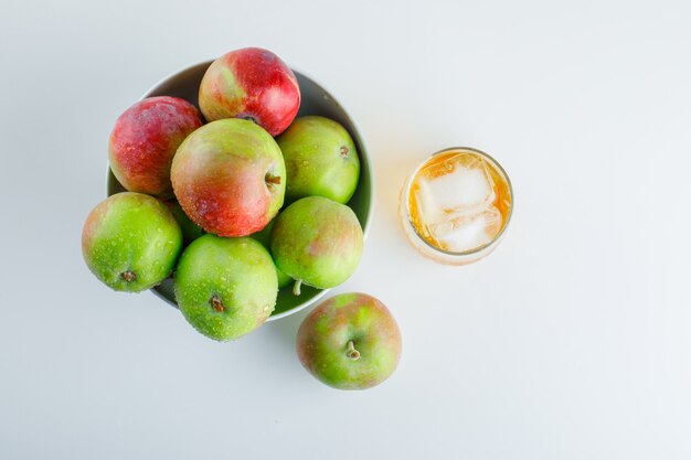 Äpfel mit Getränk in einer Schüssel auf Weiß