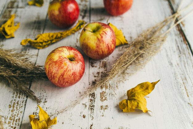 Äpfel mit trockenen Blättern auf schäbiger Tabelle