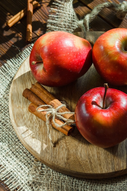 Äpfel mit Zimtstangen auf Schneidebrett