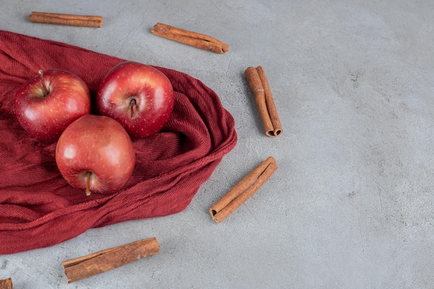 Äpfel umgeben von Zimtschnitten auf Marmoroberfläche.