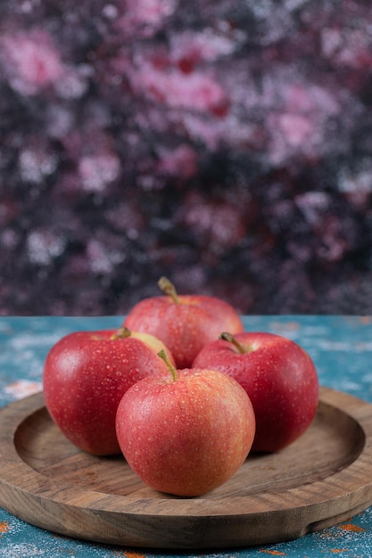 Äpfel werden auf runder Holzplatte serviert.