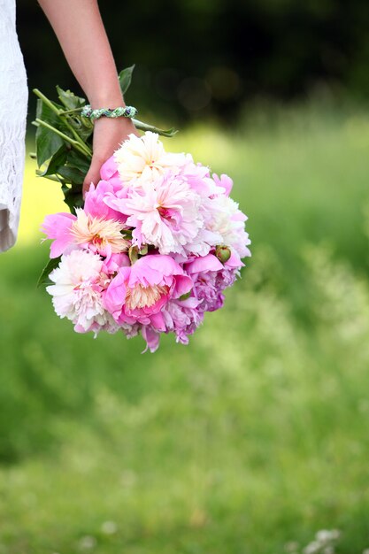 Pfingstrosenblumenstrauß in der Hand der Frau draußen