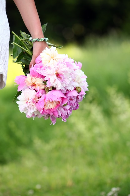 Pfingstrosenblumenstrauß in der Hand der Frau draußen