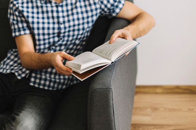 Pflanzen Sie den Mann, der auf Sofa mit Buch stillsteht