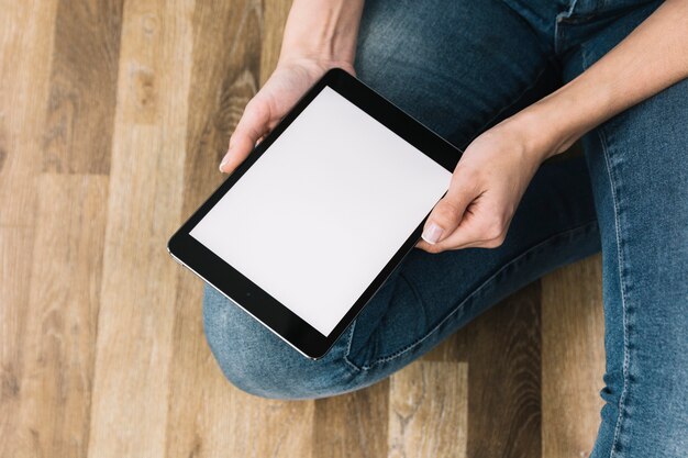 Pflanzen Sie Frau mit der Tablette, die auf Boden sitzt