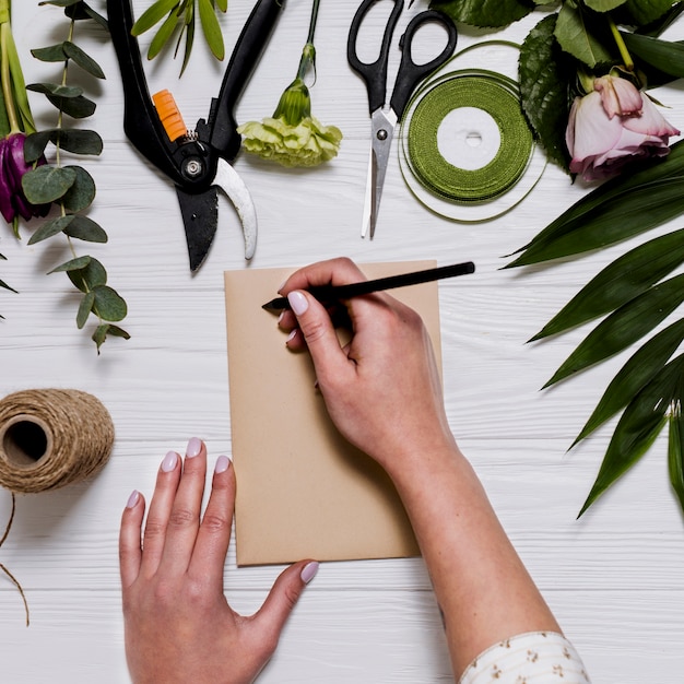 Pflanzen Sie Handschrift auf Tabelle mit Floristenausrüstung