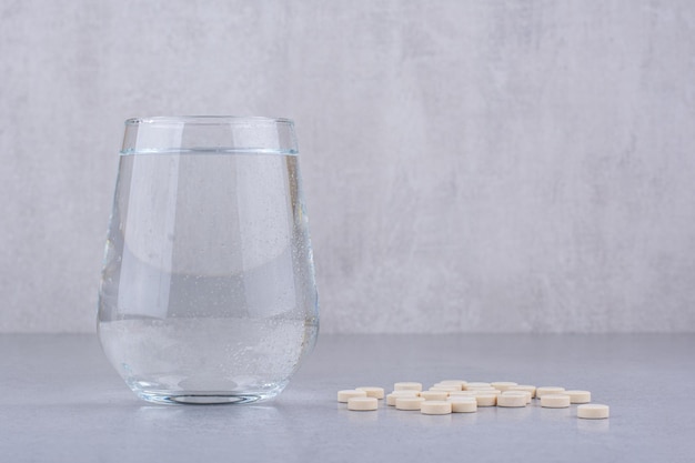 Pharmazeutische Medizinpillen und ein Glas Wasser. Foto in hoher Qualität